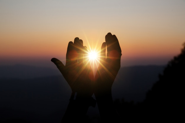 priere-spirituelle-mains-soleil-brille-beau-coucher-soleil-floue_1150-7173